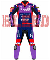 Front view of the Prima Pramac Yamaha MotoGP 2025 racing suit for rider Jack Miller, displaying prominent sponsor logos such as Prima on the chest and back, along with Alpine, Pramac, Yamaha, and the newly added "BLEED" logo on the arms and legs. The suit is primarily blue with red and purple accents. The back of the suit clearly shows the rider name "MILLER"